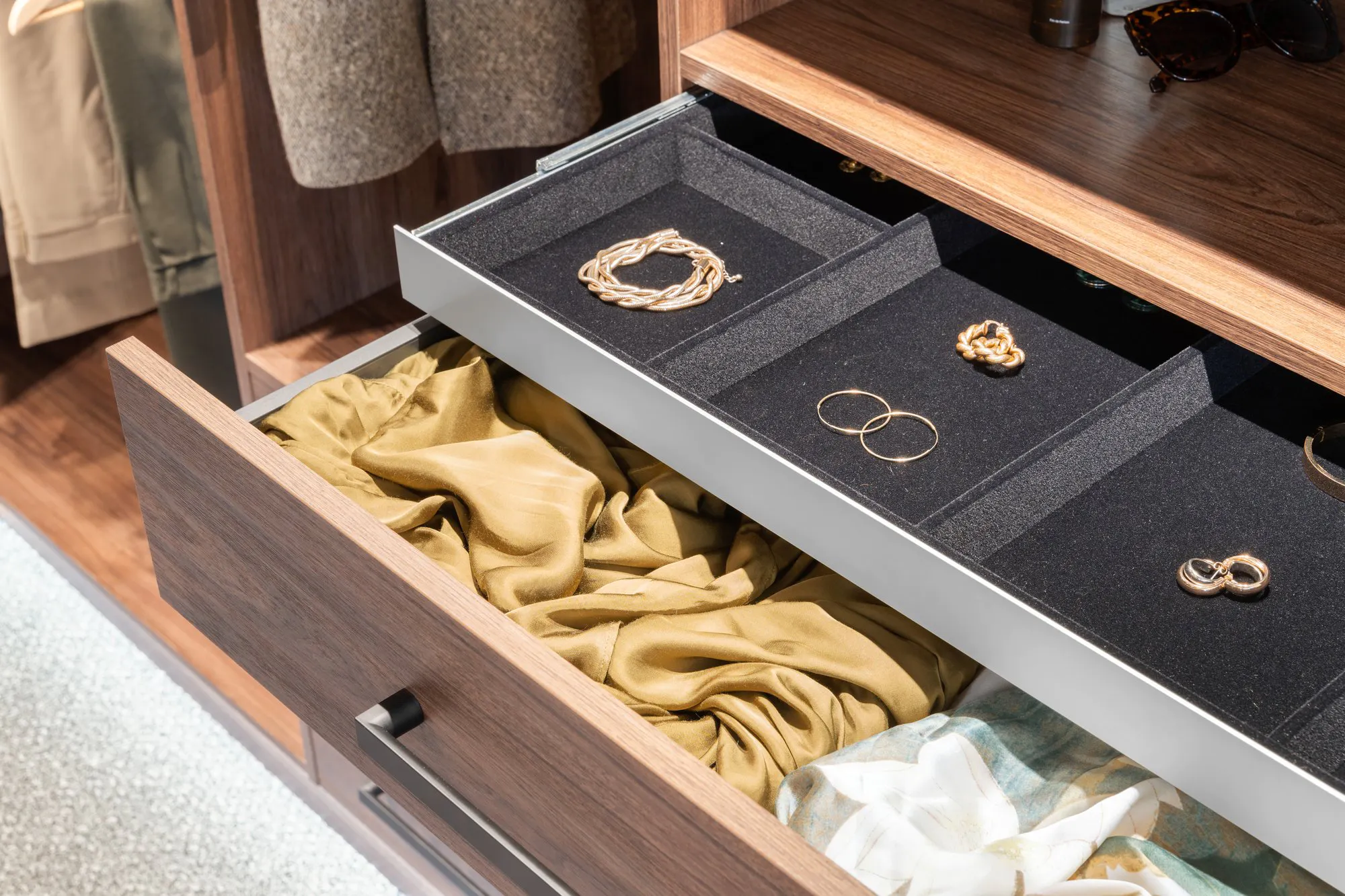 Jewellery drawer in a wardrobe is open showing earrings and bracelents