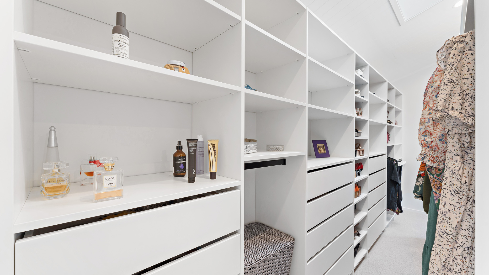 White Flex wardrobe organiser walk-in, you can see 3 drawer towers, a shoe tower, and some perfume and makeup bottles on the shelf